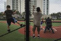 Boys climb a protective fence as they watch a little league baseball game in Miami, Florida April 3, 2016. REUTERS/Carlo Allegri