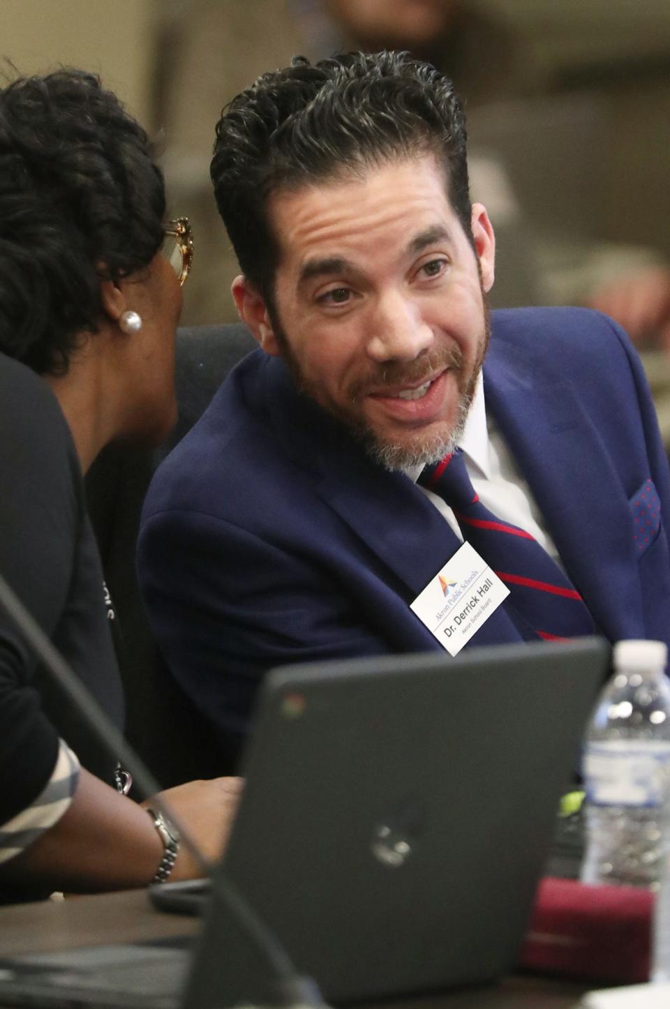 Akron school board member Carla Jackson whispers to Vice President Derrick Hall before the vote to elect Hall as president of the board during a meeting in January in Akron.