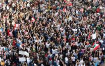 Demonstrators carry national flags and gesture during an anti-government protest in Beirut