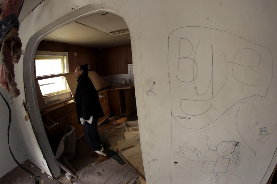 In this photo taken Monday, Nov. 18, 2019, Tammy Kilgore walks through her home for the final time before it was demolished as part of a voluntary buyout in flood-prone Mosby, Mo. Kilgore accepted a $45,000 payment to leave her home of 38 years and has moved to a nearby community. (AP Photo/Charlie Riedel)