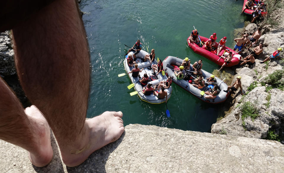 A man prepares to jump in the Neretva river near the town of Konjic, Bosnia, Saturday, July 2, 2022. It took a decade of court battles and street protests, but Balkan activists fighting to protect some of Europe's last wild rivers have scored an important conservation victory in Bosnia. A new electricity law, which passed Thursday, bans the further construction of small hydroelectric power plants in the larger of Bosnia's two independent entities. (AP Photo/Eldar Emric)