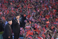 FILE - In this file photo released by China's Xinhua News Agency, spectators wave Chinese and North Korean flags as North Korean leader Kim Jong Un, left, and visiting Chinese President Xi Jinping attend a mass gymnastic performance at the May Day Stadium in Pyongyang, North Korea Thursday, June 20, 2019. China appears to be keeping its distance as Russia and North Korea move closer to each other with a new defense pact that could tilt the balance of power between the three authoritarian states. (Yan Yan/Xinhua via AP, File)