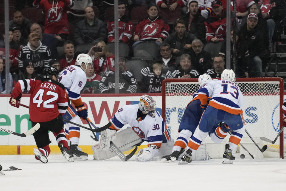 New Jersey Devils' Curtis Lazar (42), left, scores the winning goal past New York Islanders goaltender Ilya Sorokin (30), center, during the third period of an NHL hockey game in Newark, N.J., Tuesday, Nov. 28, 2023. The Devils defeated the Islanders 5-4. (AP Photo/Seth Wenig)