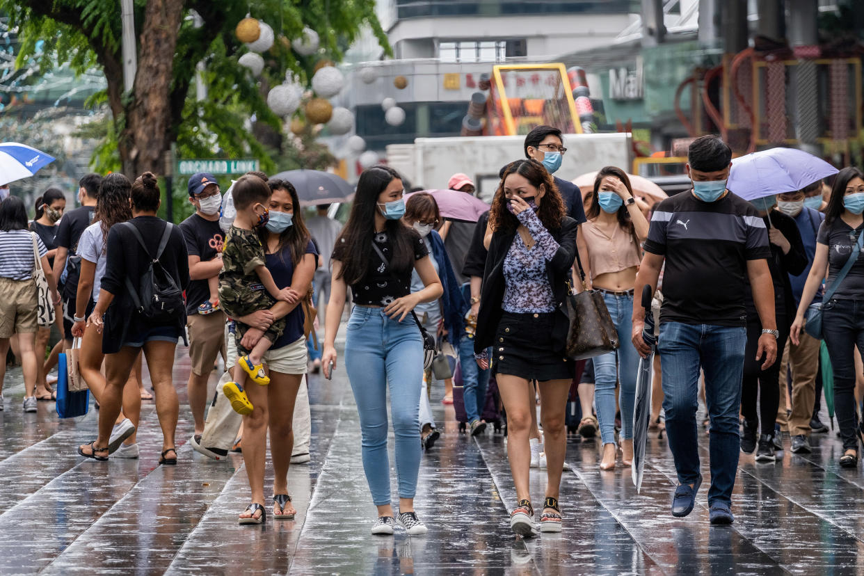 SINGAPORE - 2020/11/21: People wearing face masks as a preventive measure against the covid19 coronavirus walk along the Orchard Road after a downpour. Orchard Road is a famous shopping district in Singapore, lined with luxury-branded stores, delightful restaurants, and popular hotels. As of 23 November 2020, Singapore has recorded a total of 58,160 Covid-19 coronavirus cases, 28 infected patients died as a result. (Photo by Maverick Asio/SOPA Images/LightRocket via Getty Images)