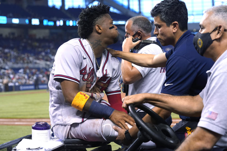 Atlanta Braves right fielder Ronald Acuna Jr., left, leaves the field on a medical cart after trying to make a catch on an inside-the-park home run hit by Miami Marlins' Jazz Chisholm Jr. during the fifth inning of a baseball game Saturday, July 10, 2021, in Miami. (AP Photo/Lynne Sladky)