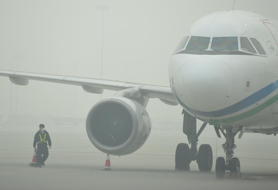 An airport ground crew worker wears a mask in thick smog on the tarmac of Hongqiao airport in Shanghai as severe pollution blankets the city on December 6, 2013. The cities most harmful PM2.5 density soared to 468 micrograms per cubic metre by midnight more than 10 times the level deemed safe by the World Health Organization state media said. AFP PHOTO/Peter PARKS        (Photo credit should read PETER PARKS/AFP/Getty Images)