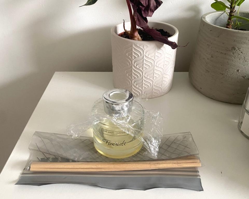 The White Company reed diffuser covered in cling film with reeds in bag beside it