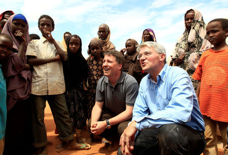 FILE PHOTO: Britain's Secretary of State for International Development Andrew Mitchell (2nd R) and NGO Save the Children Chief Executive Justin Forsyth (C) talk with newly-arrived refugees at the Dagahaley refugee camp in Dadaab, near Kenya's border with Somalia, July 16, 2011. Mitchell visited Dadaab refugee camps, where he met displaced families forced to leave their homes in Somalia in order to survive. REUTERS/Thomas Mukoya/File Photo