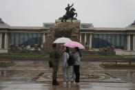 FILE - Young Mongolians chat under umbrellas as it rains on Sukhbaatar Square in Ulaanbaatar, Mongolia on Thursday, June 27, 2024. Younger voters historically have not voted in large numbers, but anecdotal reports suggest their turnout may have risen in Ulaanbaatar in last week's Parliament election. (AP Photo/Ng Han Guan, File)