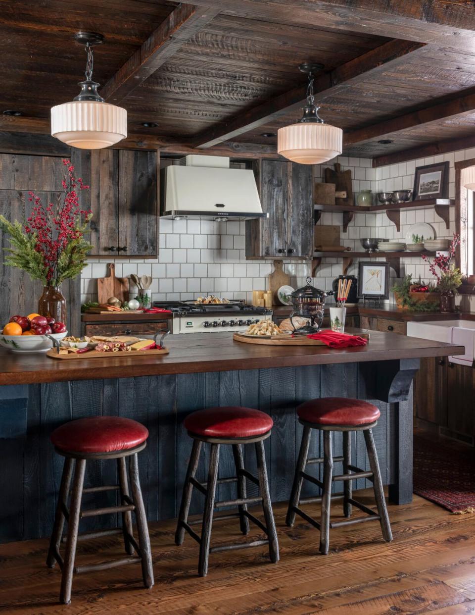 a corner of a farmhouse kitchen with a dark blue island and red topped counterstools