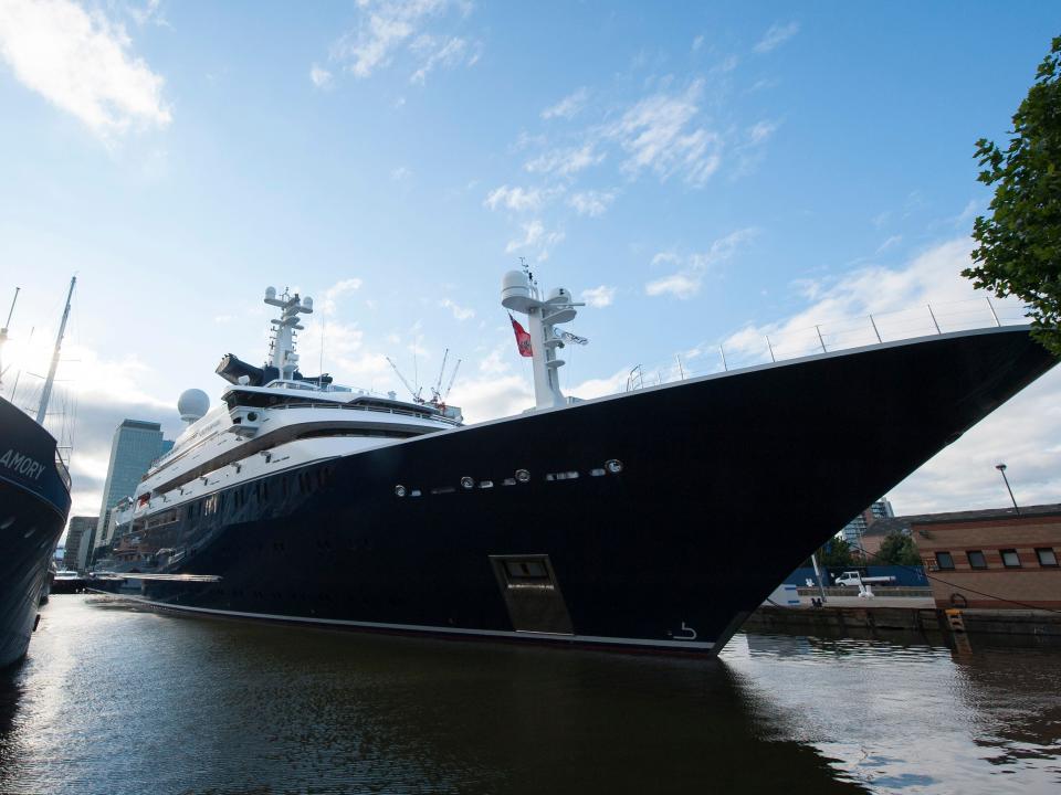 The blue hull of the luxury yacht "Octopus" sits at the dock in London's Canary Wharf