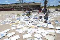 Schoolchildren pick up books left to dry in the sun after their school was damaged by Cyclone Idai in Inchope, Mozambique, Monday March, 25, 2019. Cyclone Idai's death toll has risen above 750 in the three southern African countries hit 10 days ago by the storm, as workers rush to restore electricity, water and try to prevent outbreak of cholera. (AP Photo/Tsvangirayi Mukwazhi)