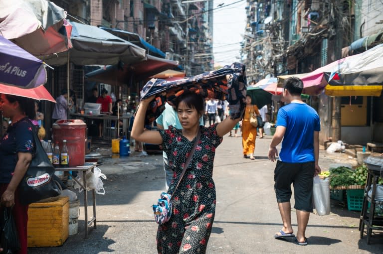 Una mujer se refugia del sol mientras camina por una calle en un día caluroso en Rangún, el 25 de abril de 2024 (Sai Aung MAIN)