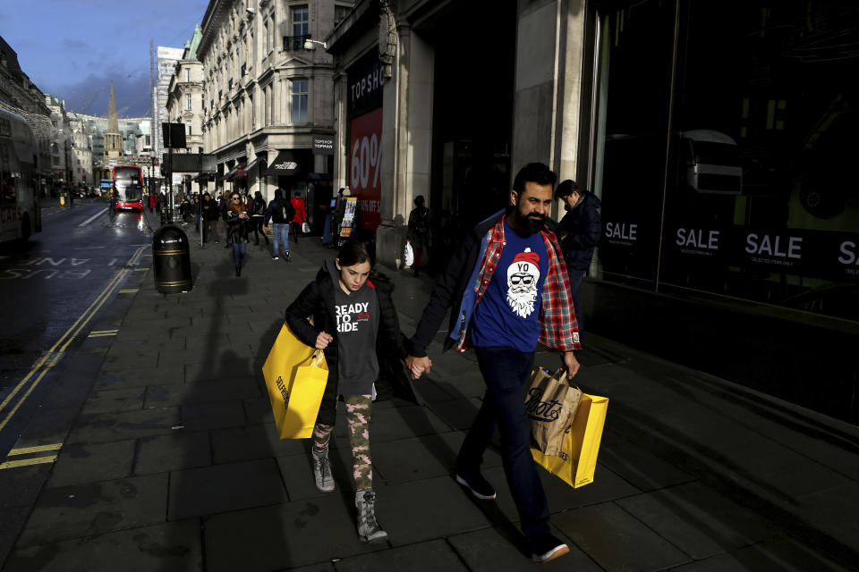 People with shopping bags walk on Oxford street in a last day before Christmas in central London, England, Tuesday, Dec. 24, 2019. (AP Photo/Petros Karadjias)