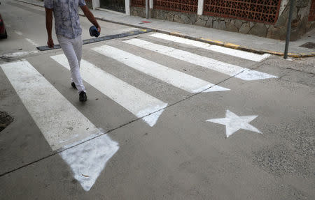 A man walks past a crosswalk, painted in the form of an Estelada (Catalan pro-independence flag) in Arenys de Munt, north of Barcelona, Spain, September 26, 2017. REUTERS/Albert Gea