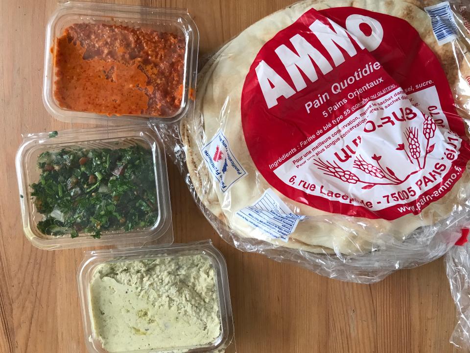 three containers of dips and spreads next to a pack of flatbread