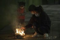 A family burn paper offerings for their departed relatives on the streets of Wuhan in central China's Hubei province on Saturday, April 4, 2020. Authorities are controlling access and limiting the number of people entering cemeteries across China during the annual Qingming festival, also known as the Grave Sweeping Day, a day when Chinese around the world remember their dearly departed and take time off to clean up the tombs and place flowers and offerings, a move to prevent the spread of the new coronavirus outbreak. (AP Photo/Ng Han Guan)