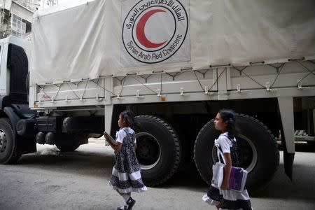 Twin girls walk near a Red Crescent aid convoy carrying urgent medical supplies in the rebel held besieged town of Douma, eastern Ghouta in Damascus, Syria May 26, 2016. REUTERS/Bassam Khabieh