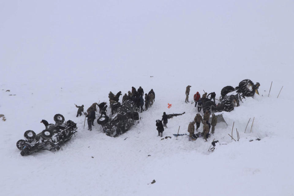 Emergency service members dig in the snow around at least three overturned vehicles, near the town of Bahcesehir, in Van province, eastern Turkey, Wednesday, Feb. 5, 2020. Some dozens of rescue workers are missing after being hit by a second avalanche while on a mission to find two people missing in a previous snow-slide that struck late Tuesday, burying a snow-clearing vehicle and a minibus. (DHA via AP)
