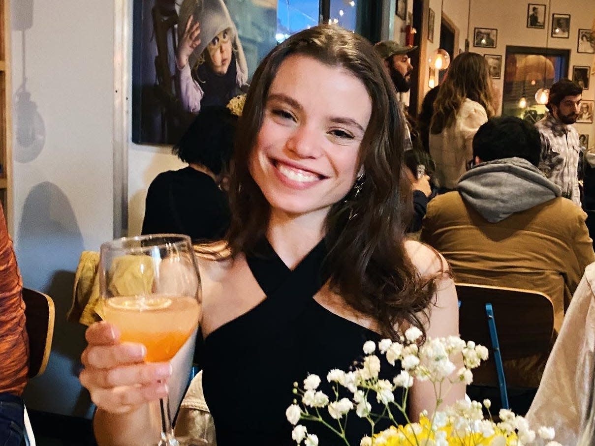 Emma Ginsberg holding up a drink at a restaurant