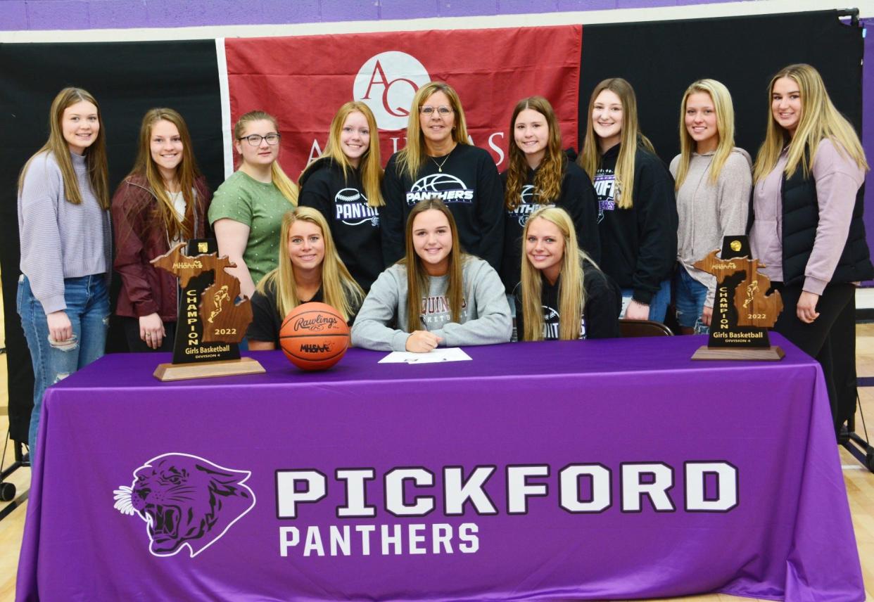 Kennedy Guild, front center, signs with Aquinas College women's basketball. Guild was joined by her coach and teammates as she signed Wednesday.