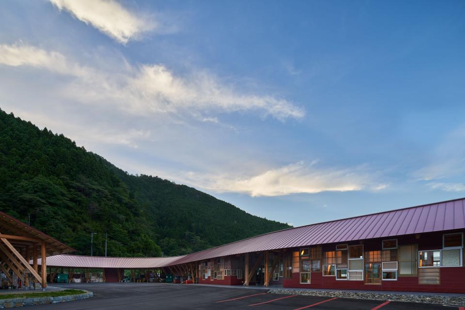The exterior of the zero waste center is seen with a hill in the background on a partly-cloudy day.
