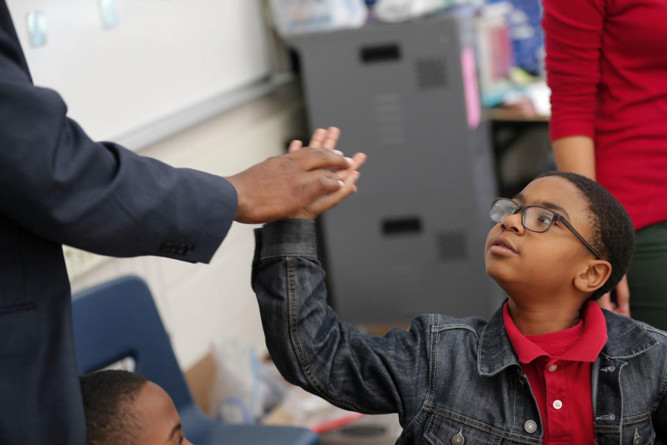 In this Tuesday, Dec. 18, 2018 photo, second grader Maleki Ratliff high-fives Jamar McKneely, chief executive officer of InspireNOLA Charter Schools, at Alice M. Harte Charter School in New Orleans. Charter schools, which are publicly funded and privately operated, are often located in urban areas with large back populations, intended as alternatives to struggling city schools. (AP Photo/Gerald Herbert)