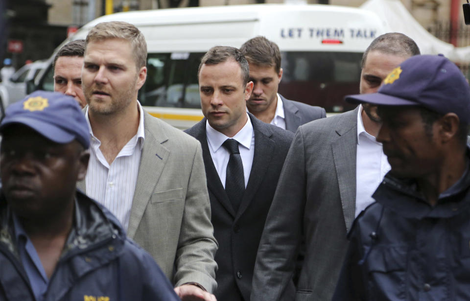 Oscar Pistorius, center rear, arrives at the high court for the third day of his trial in Pretoria, South Africa, Wednesday, March 5, 2014. Pistorius is charged with murder with premeditation in the shooting death of girlfriend Reeva Steenkamp in the pre-dawn hours of Valentine's Day 2013. (AP Photo/Schalk van Zuydam)