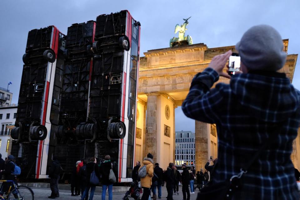 Berlin: A visitor snaps a photo of three buses standing on end that make up an art installation called