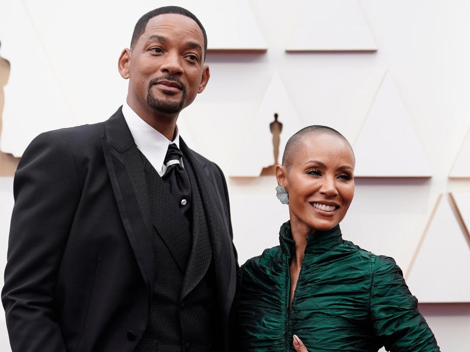 Will in a black suit and Jada in a shiny green long sleeve dress.