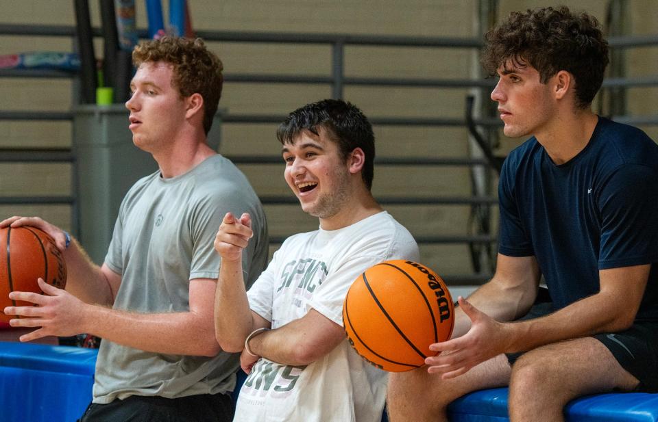 Organizer Spencer Mirken reacts to seeing a familiar player enter the gym before a pickup basketball league game at Mills Town Hall as players Jackson McKersie, left, and Noah Beaudet, right, wait for play to begin Monday.