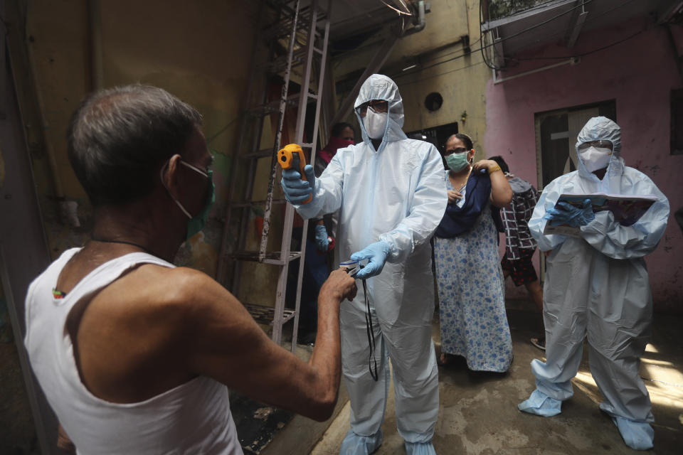 A doctor checks the temperature of a man during a free medical camp in Dharavi, one of Asia's largest slums in Mumbai, India, Saturday, June 20, 2020. India is the fourth hardest-hit country by the COVID-19 pandemic in the world after the U.S., Russia and Brazil. (AP Photo/Rafiq Maqbool)