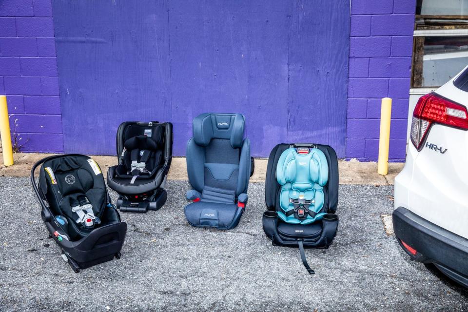 four car seats on the ground next to a car