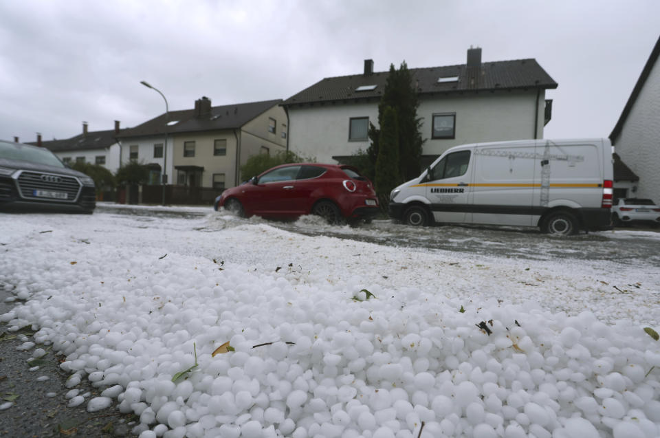 Hail lies on a sidewalk and drifts on a flooded street in Augsburg, Germany, Saturday Aug. 26, 2023. A storm with large hailstones damaged four-fifths of the buildings in a small town in the southern German state of Bavaria, local authorities said Sunday. The storm swept across the southern part of Bavaria on Saturday. In Kissing, just outside Augsburg, police said 12 people were injured when a beer tent that they were trying to put up was blown over. (Karl-Josef Hildenbrand/dpa via AP)