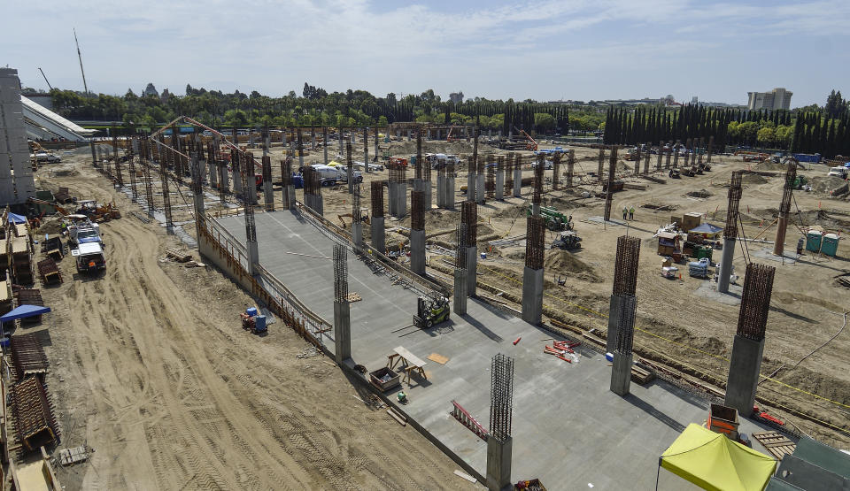 Rows of rebar sprout from the ground on a parking lot under construction.