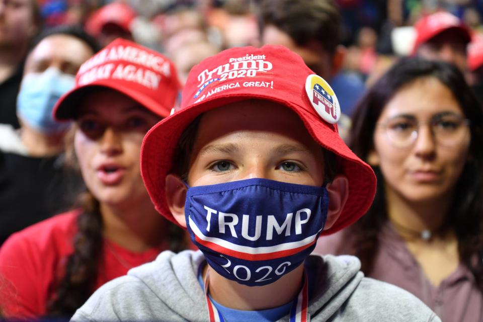 A young supporter wears a Trump 2020 mask as he listens to US President Donald Trump speak during a campaign rally at the BOK Center on June 20, 2020 in Tulsa, Oklahoma. - Hundreds of supporters lined up early for Donald Trump's first political rally in months, saying the risk of contracting COVID-19 in a big, packed arena would not keep them from hearing the president's campaign message. (Photo by Nicholas Kamm / AFP) (Photo by NICHOLAS KAMM/AFP via Getty Images)