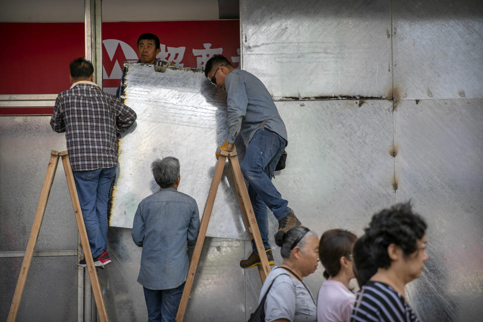 Workers install welded metal plates around the entrance of a China Merchants Bank branch in Hong Kong, Friday, Oct. 25, 2019. Banks, retailers, restaurants and travel agents in Hong Kong with ties to mainland China or perceived pro-Beijing ownership have fortified their facades over apparent concern about further damage after protesters trashed numerous businesses following a recent pro-democracy rally. (AP Photo/Mark Schiefelbein)