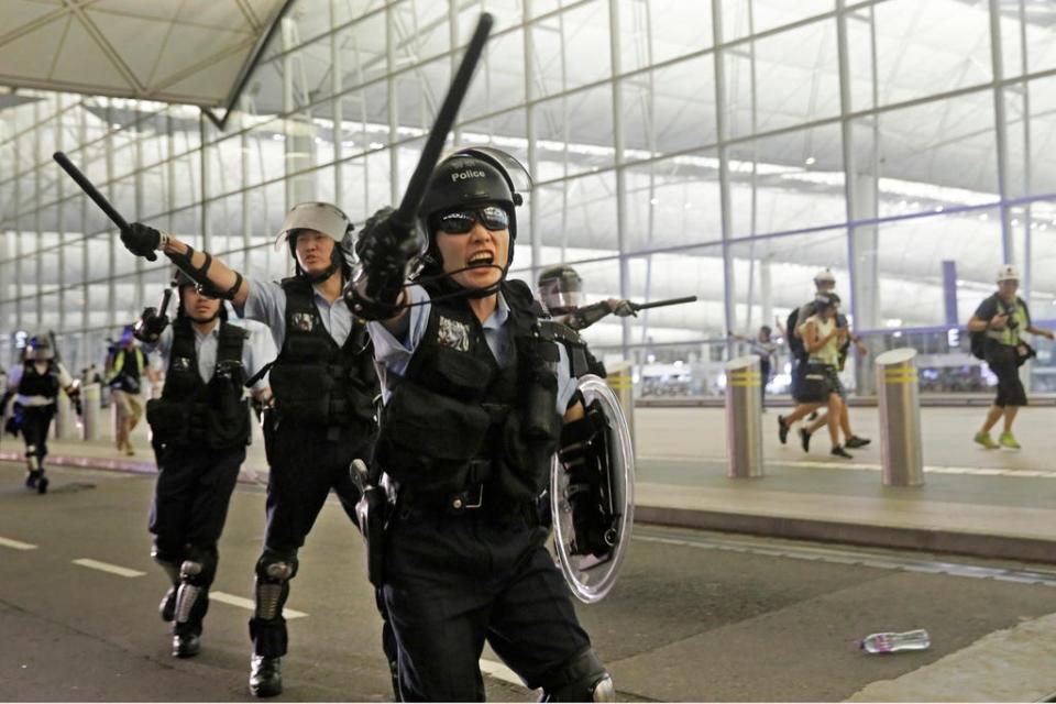 Policemen with batons and shields shout at protesters during a demonstration at the Airport in Hong Kong, Tuesday, Aug. 13, 2019. (AP Photo/Vincent Yu)