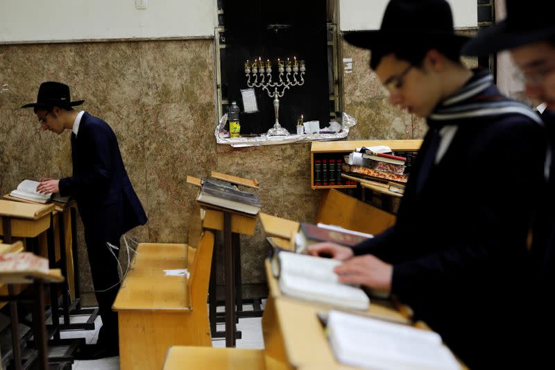 Jewish seminary students read religious texts after lighting a hanukkiyah, a candlestick with nine branches that is lit to mark Hanukkah, the 8-day Jewish Festival of Lights, at their seminary of Yeshiva, in Bnei Brak, Israel