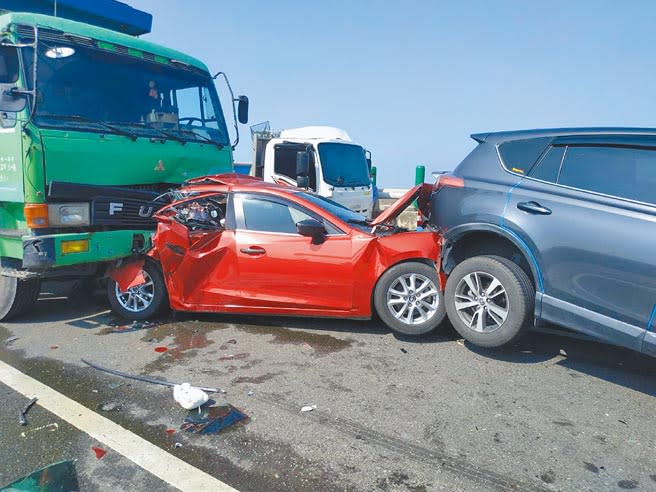西濱快速公路雲林縣、嘉義縣交界處2死8傷車禍，1輛轎車被追撞夾在2車之間。（張朝欣攝）
