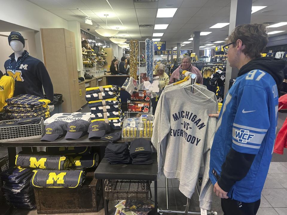 A customer at The M Den, a retail store near the University of Michigan campus in Ann Arbor, Mich. Sunday, Nov. 12, 2023 takes a look at Michigan Vs. Everybody merchandise. The second-ranked Wolverines headed into a fateful week with a court hearing, a road trip to Maryland and a swagger built on their growing belief that it's them against the world. "Michigan vs. Everybody" merchandise was flying off the racks Sunday as the school prepared for its legal battle fight to free Jim Harbaugh from a Big Ten suspension. (AP Photo/Larry Lage)