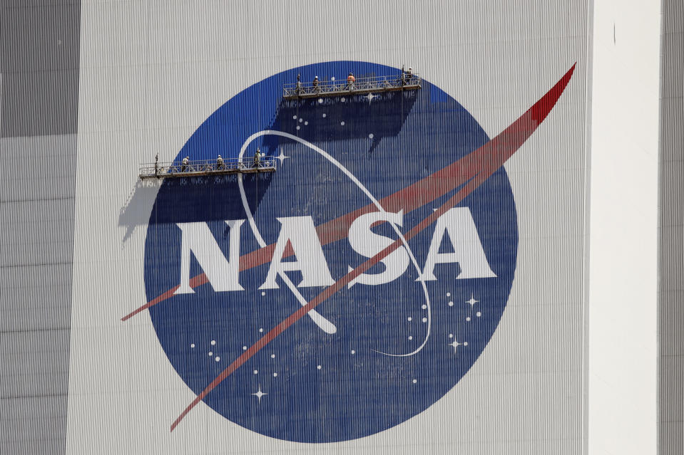 Workers near the top of the 526 ft. Vehicle Assembly Building at the Kennedy Space Center spruce up the NASA logo standing on scaffolds in Cape Canaveral, Fla., Wednesday, May 20, 2020. A SpaceX Falcon 9 rocket scheduled for May 27 will launch a Crew Dragon spacecraft on its first test flight with astronauts on-board to the International Space Station. (AP Photo/John Raoux)