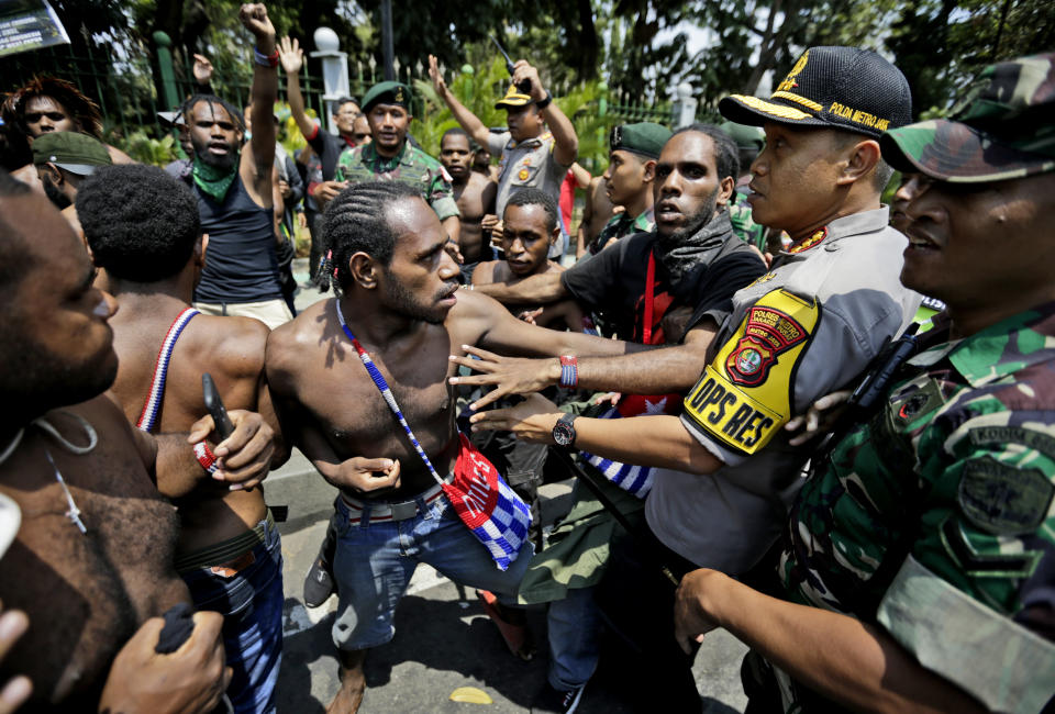 Papuan activists scuffle with police and soldiers during a rally near the presidential palace in Jakarta, Indonesia, Thursday, Aug. 22, 2019. A group of West Papuan students in Indonesia's capital staged the protest against racism and called for independence for their region. (AP Photo/Dita Alangkara)