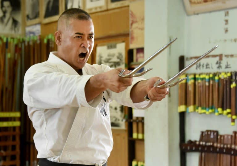 Karate master Mamoru Nakamoto, a high-ranking expert of the Okinawa Kobudo traditional weapons system, using a pair of 'sai' to demonstrate his skills at a training hall in Naha