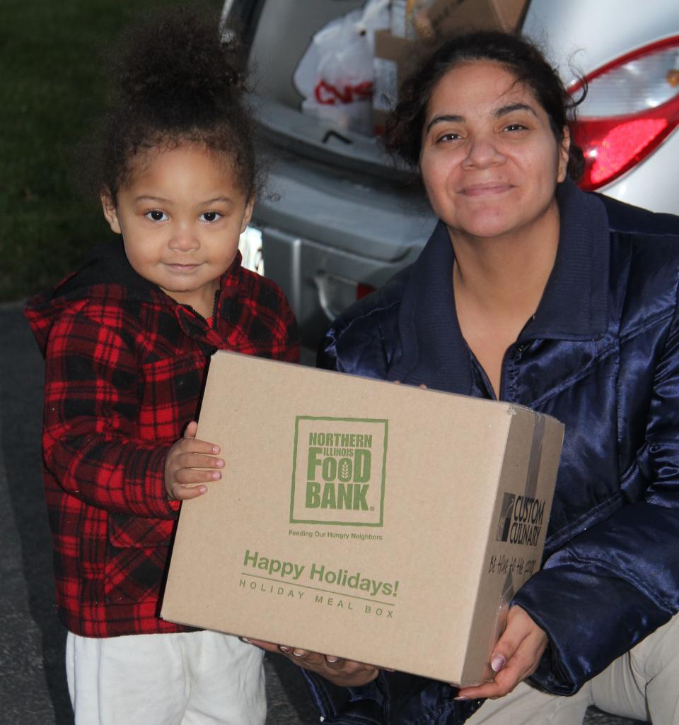 Veronica and her 2-year-old daughter receive a holiday meal box at Open Arms Mission Food Pantry in Antioch, Illinois, in 2016. The Northern Illinois Food Bank's meal boxes are packed with a turkey or ham, potatoes and other traditional holiday foods&nbsp;for a family of eight. (Photo: Northern Illinois Food Bank)