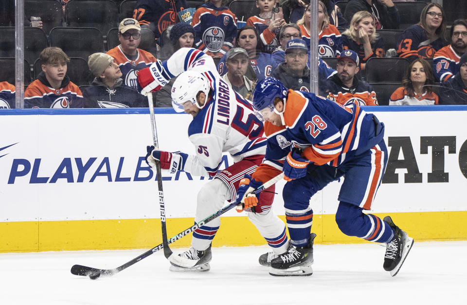 New York Rangers' Ryan Lindgren (55) and Edmonton Oilers' Connor Brown (28) vie for the puck during the second period of an NHL hockey game Thursday, Oct. 26, 2023, in Edmonton, Alberta. (Jason Franson/The Canadian Press via AP)