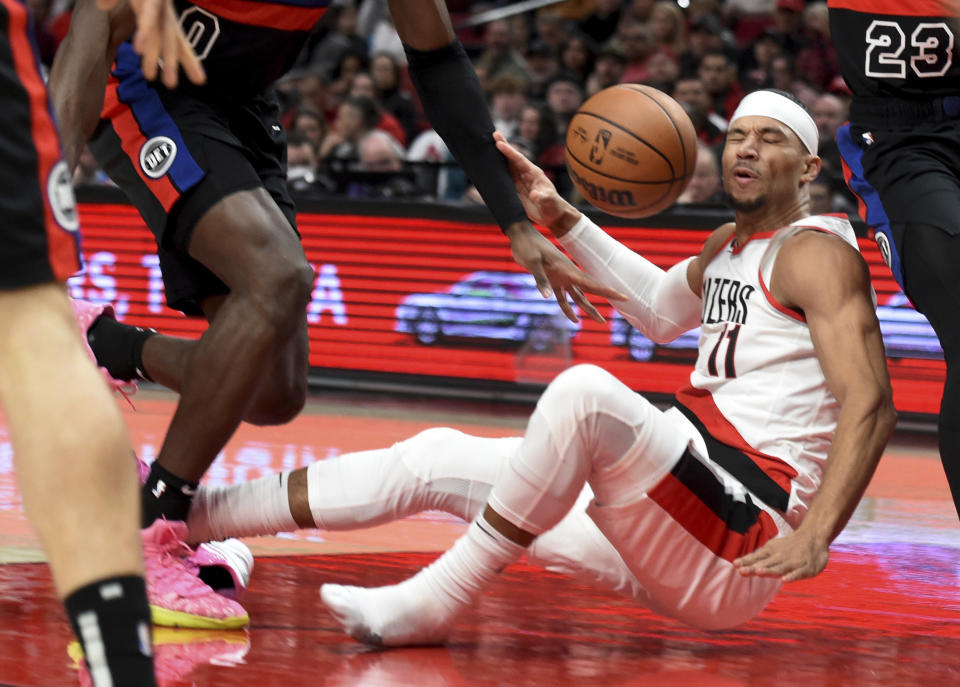 Portland Trail Blazers guard Josh Hart, center, has the ball bounce off his face as he drives to the basket on Detroit Pistons center Jalen Duren, left, and guard Jaden Ivey, right, during the first half of an NBA basketball game in Portland, Ore., Monday, Jan. 2, 2023. (AP Photo/Steve Dykes)