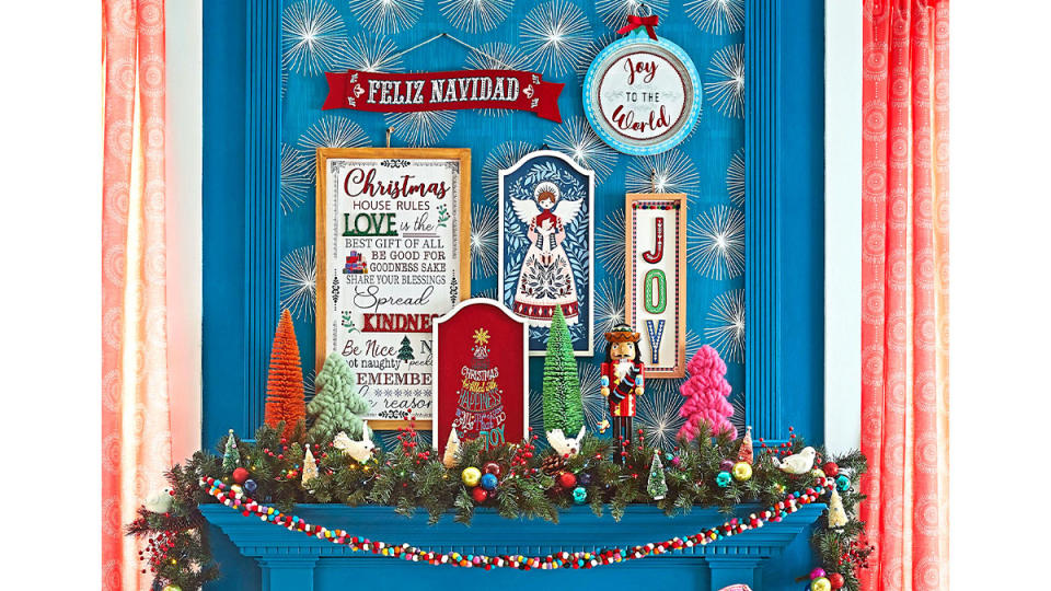 Christmas mantel ideas: Mid-century modern style mantel with colorful sisal trees, artwork and garlands on a blue fireplace mantel