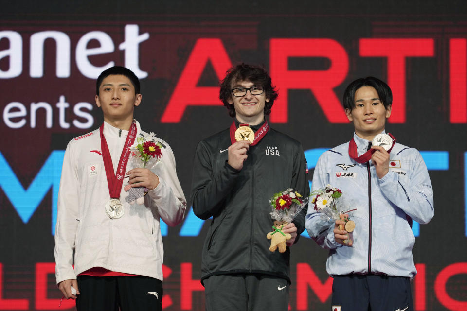 Stephen Nedoroscik, center, of the U.S., with his gold medal, and the two silver medalists, Weng Hao, left, of China, and Kazuma Kaya, of Japan, pose for photos and video during the victory ceremony for the men's pommel horse final in the FIG Artistic Gymnastics World Championships in Kitakyushu, western Japan, Saturday, Oct. 23, 2021. (AP Photo/Hiro Komae)