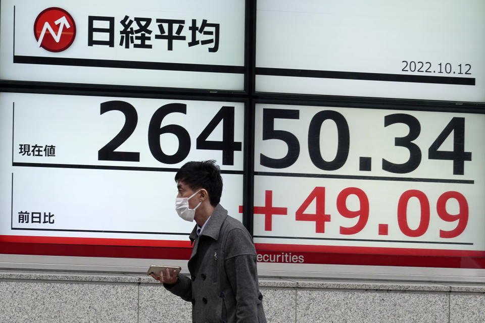 A person walks in front of an electronic stock board showing Japan's Nikkei 225 index at a securities firm Wednesday, Oct. 12, 2022, in Tokyo. Asian shares were mostly lower on Wednesday following another volatile day on Wall Street, as traders braced for updates on inflation and corporate earnings. (AP Photo/Eugene Hoshiko)